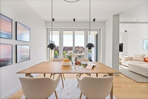 A modern dining area with a wooden table, two chairs, and a view through large windows. - Arriving between the sea, the light, and the open landscape (List auf Sylt)