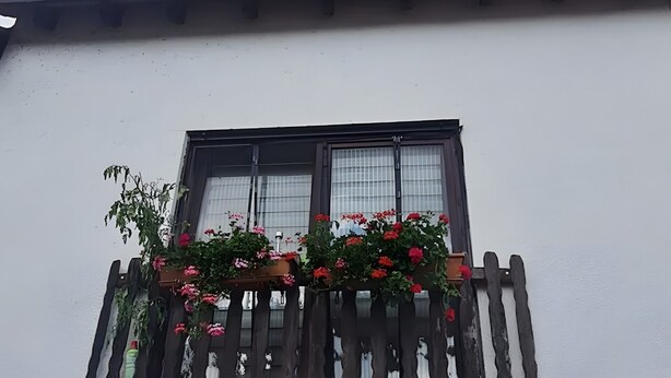 Ein Gebäude mit Balkon, Holzgeländer und Blumenkästen.