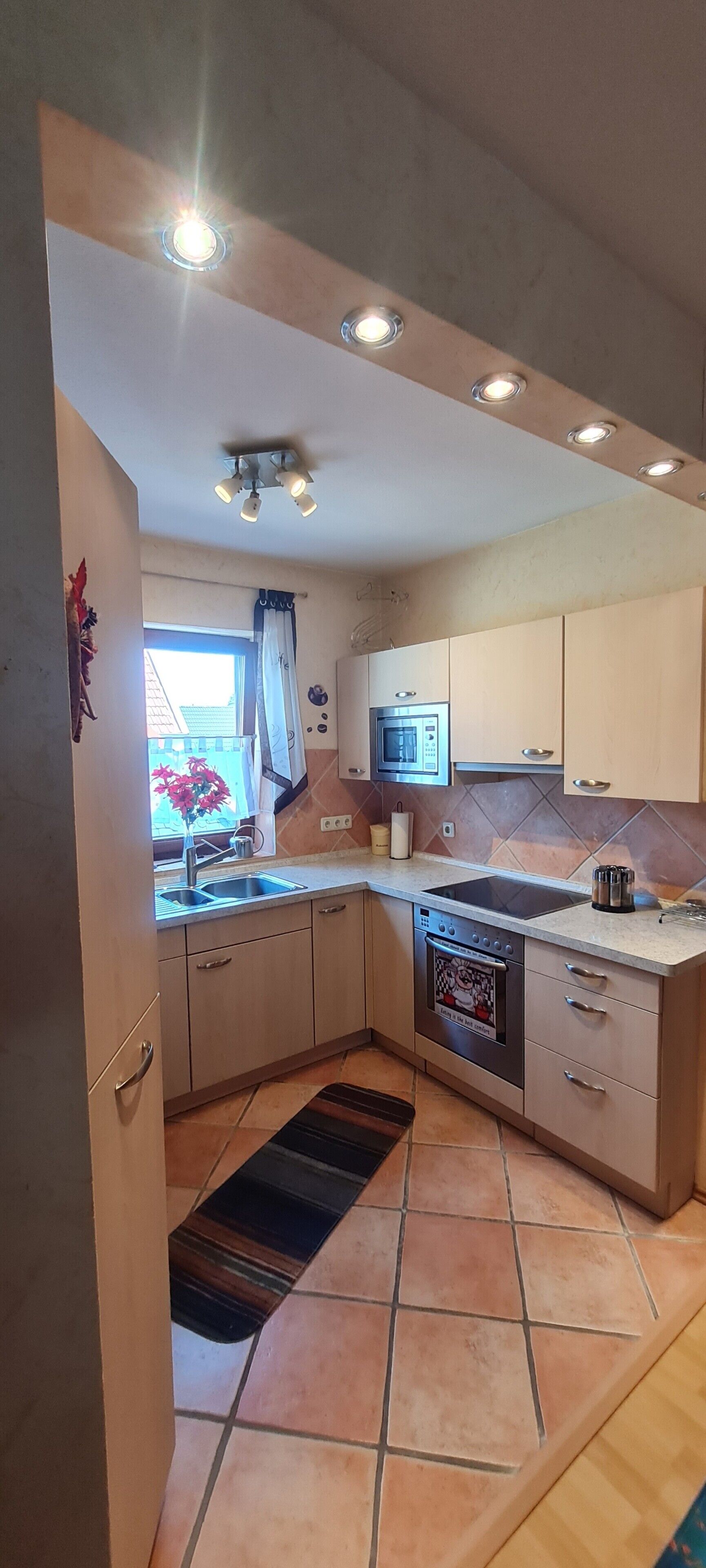 A compact kitchen with a built-in microwave, oven, and a sink.
