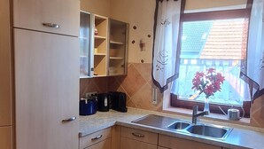 Eine kompakte Küche mit integriertem Kühlschrank, einer Spüle und einem Fenster mit Vorhängen.