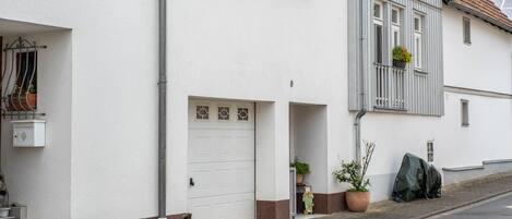 A white building with a garage door, a small window, and a mailbox.