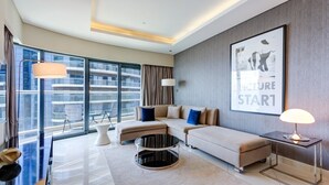 A modern living room with a sofa, coffee table, and a large window offering a city view. - Spacious 3 Bed with Burj Khalifa View l Pool & Gym (Business Bay)