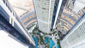 A high-rise building with a circular pool surrounded by greenery and a road. - Spacious 3 Bed with Burj Khalifa View l Pool & Gym (Business Bay)