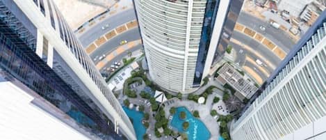 A high-rise building with a circular pool surrounded by greenery and a road.