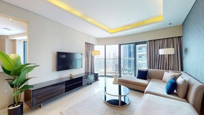 A modern living room with a sofa, TV, and a plant. - Spacious 3 Bed with Burj Khalifa View l Pool & Gym (Business Bay)