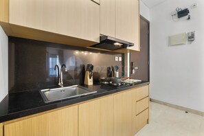 Eine moderne Küche mit Holzschränken, einer schwarzen Arbeitsplatte, einer Edelstahl-Spüle und einer eingebauten Dunstabzugshaube.