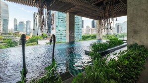 A rooftop pool with hanging sculptures, surrounded by greenery and overlooking a cityscape. - Kaeva by Kozystay - Sudirman (Central Jakarta)