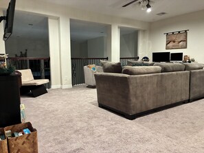 A living room with a sectional sofa, a television, and a decorative wall piece. - Spacious 3BR/3BA Upstairs Getaway with Private Balcony — Steps from  Town Center (Pearland)