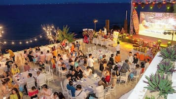 An outdoor dining area with tables and chairs arranged for guests, overlooking a body of water.