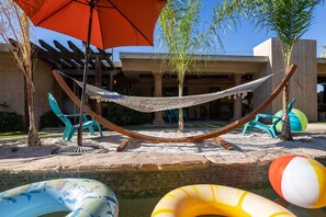 Eine Hängematte, Gartenstühle, ein Pool und Schwimmspielzeug.