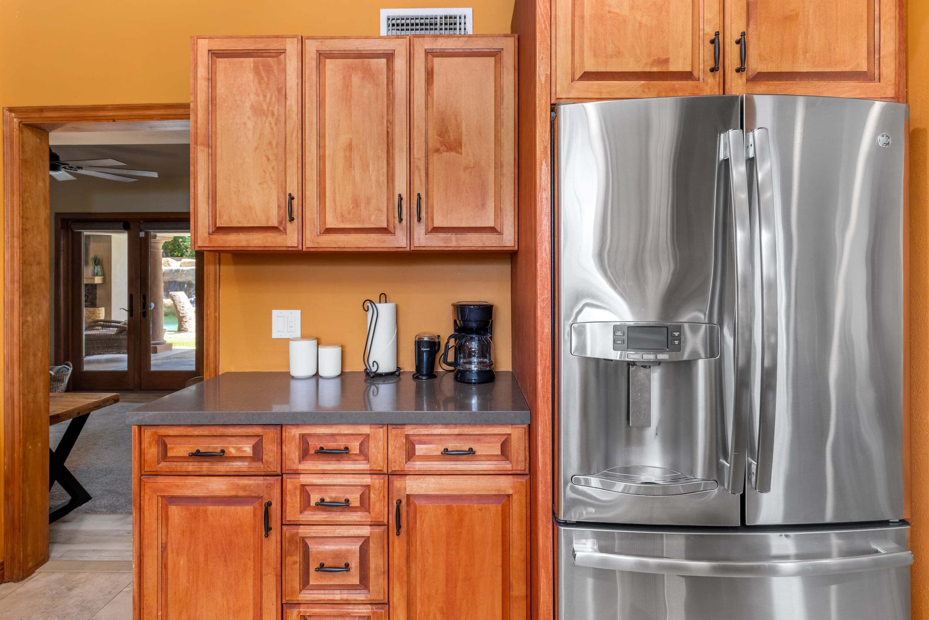 A kitchen with wooden cabinets, a stainless steel refrigerator, and a coffee maker.