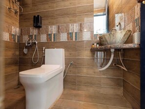 A bathroom with a shower, toilet, and sink, featuring wooden paneling and patterned tiles. - Palette Santorini Pool Mountain View (Lonavala)