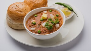 A bowl of curry with bread and a lemon wedge on a plate. - Palette Santorini Pool Mountain View (Lonavala)