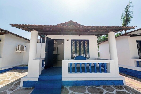 A building with a covered entrance, a staircase, and a door with a decorative grille.
