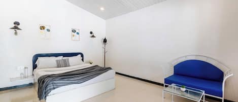 A bedroom with a bed, a blue sofa, a ceiling fan, and wall-mounted light fixtures.