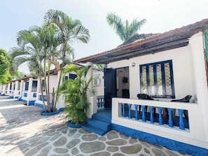 A row of white and blue buildings with stone flooring and palm trees. - Palette Santorini Pool Mountain View (Lonavala)