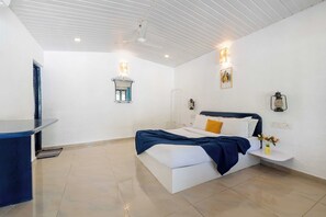 A bedroom with a bed, bedside table, wall-mounted lamp, and a small window.