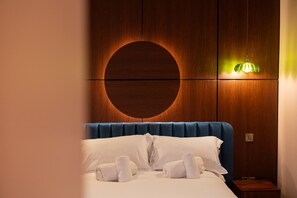 A hotel room with a circular wall design, a bed with white linens, and a green pendant light. - The Gallery - The Four Corner Collective (Sunderland)