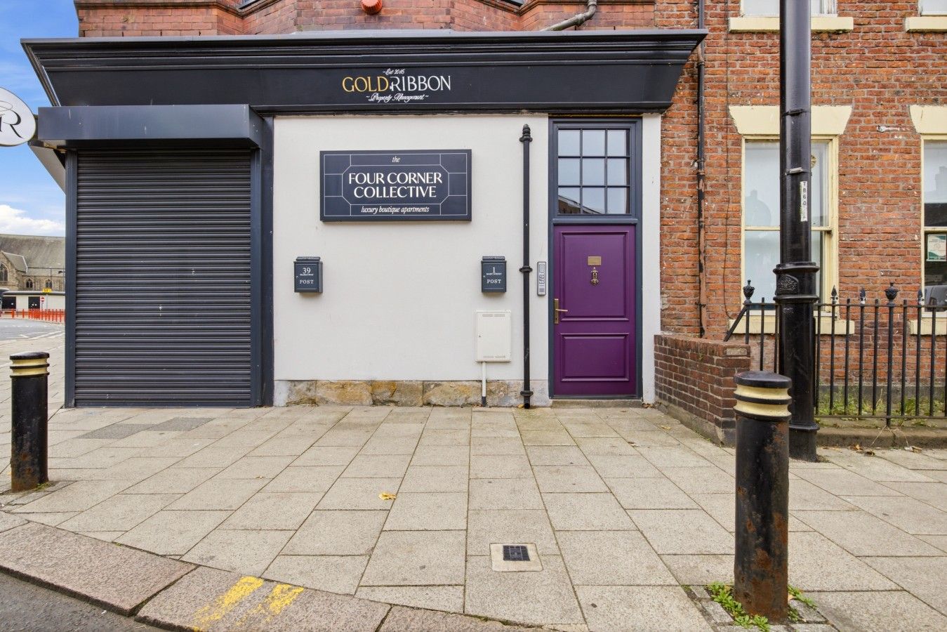 A building with a sign for 'The Four Corner Collective' and a purple door.