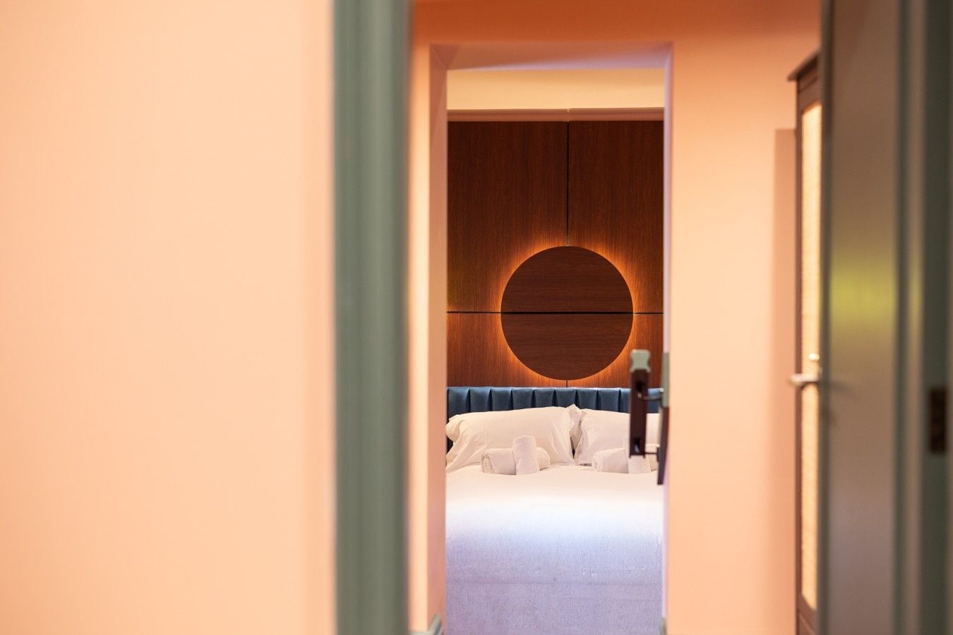 A hotel room with a circular wall design, a bed with white linens, and a nightstand.
