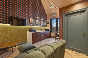 A modern kitchen with a built-in microwave, a sink, and a window. There is a seating area with a sofa and a table. - The Gallery - The Four Corner Collective (Sunderland)
