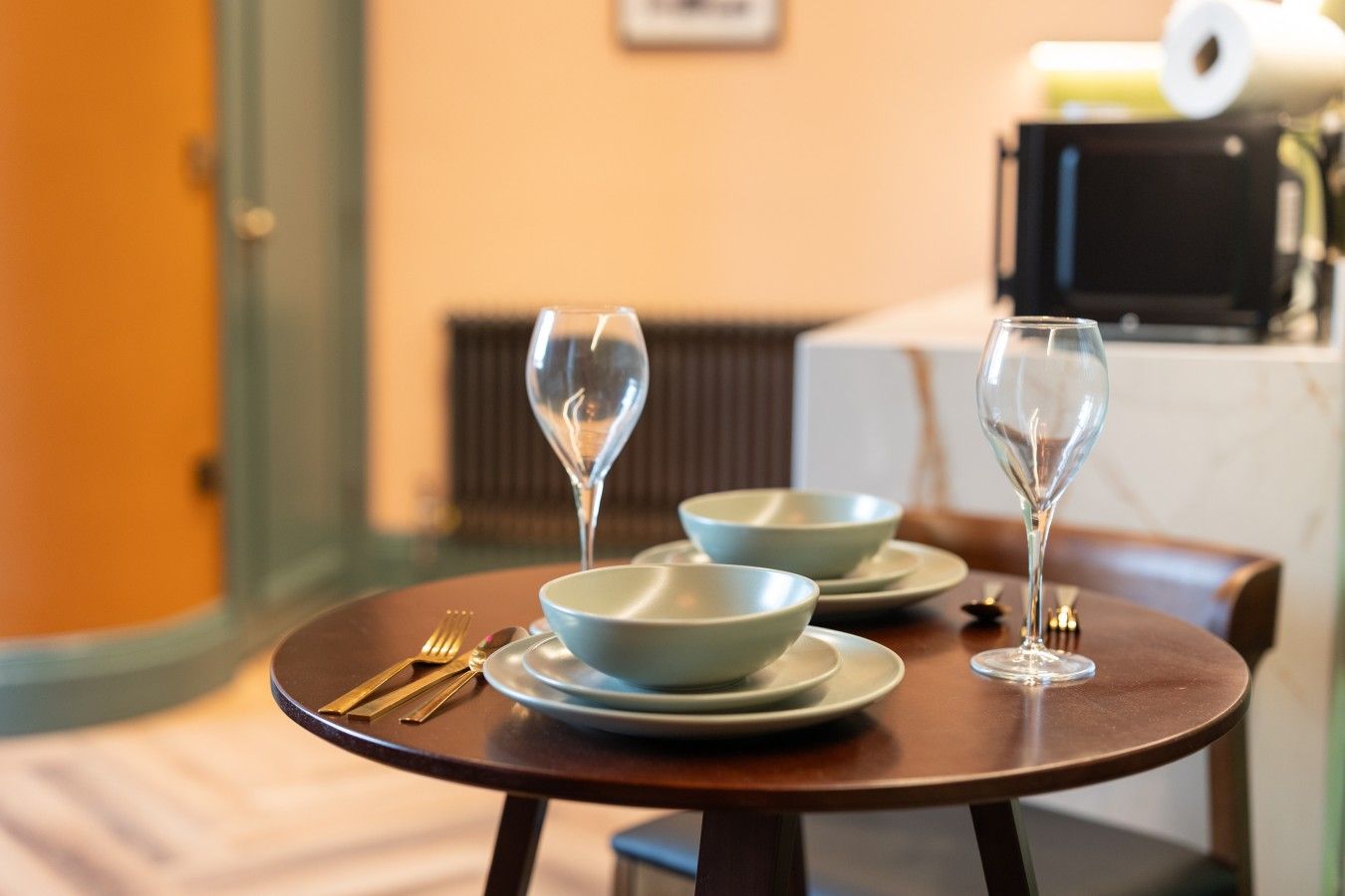 A dining table with two bowls, two wine glasses, and cutlery.