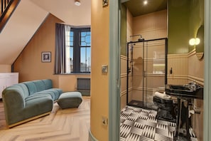 A modern interior with a sofa, a radiator, and a shower area with a patterned floor. - The Loft - The Four Corner Collective (Sunderland)