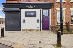 Un edificio con una insegna per 'The Four Corner Collective' e una porta viola.