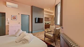 A hotel room with a bed, a desk, a chair, a TV, and a bathroom visible through an open door.