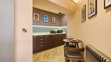 A compact kitchen with a herringbone floor pattern, wooden cabinets, a small dining table with chairs, and a radiator.