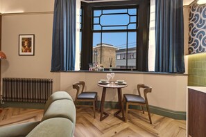 A cozy room with a dining area, a radiator, and a window with curtains. - The Pavilion - The Four Corner Collective (Sunderland)