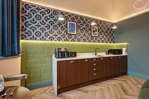 A modern kitchen with a patterned backsplash, a microwave, a coffee maker, and a sink. - The Pavilion - The Four Corner Collective (Sunderland)
