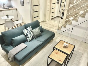 Un salon moderne avec un canapé, une table basse et une cuisine en arrière-plan.