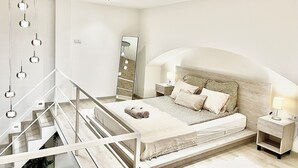 Une chambre à coucher moderne avec un lit, des tables de chevet, un miroir et un escalier.