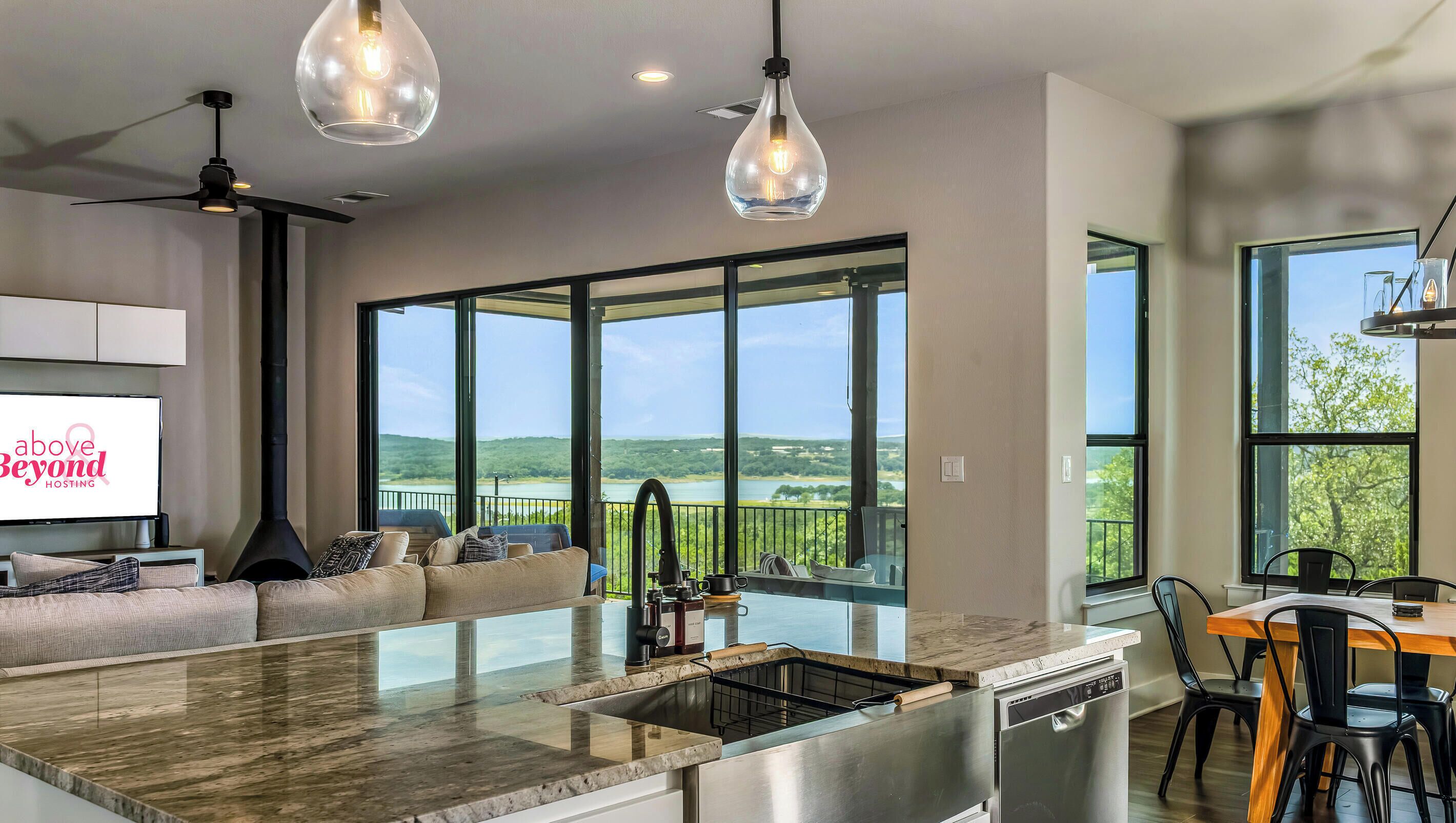 A modern kitchen with a large island, a dining area with a wooden table, and a seating area with a sofa.