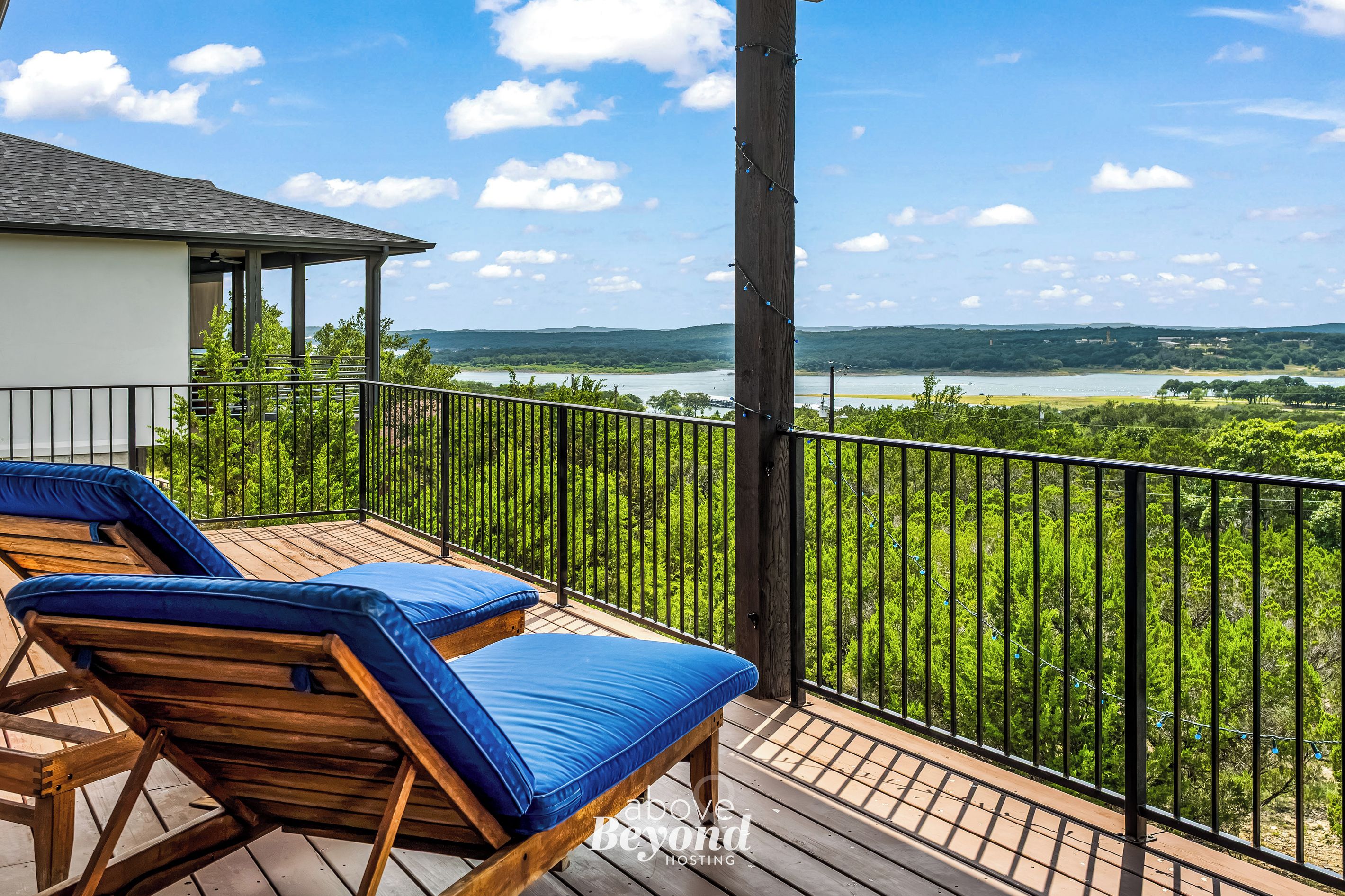 A balcony with two lounge chairs and a view of a lake and hills.
