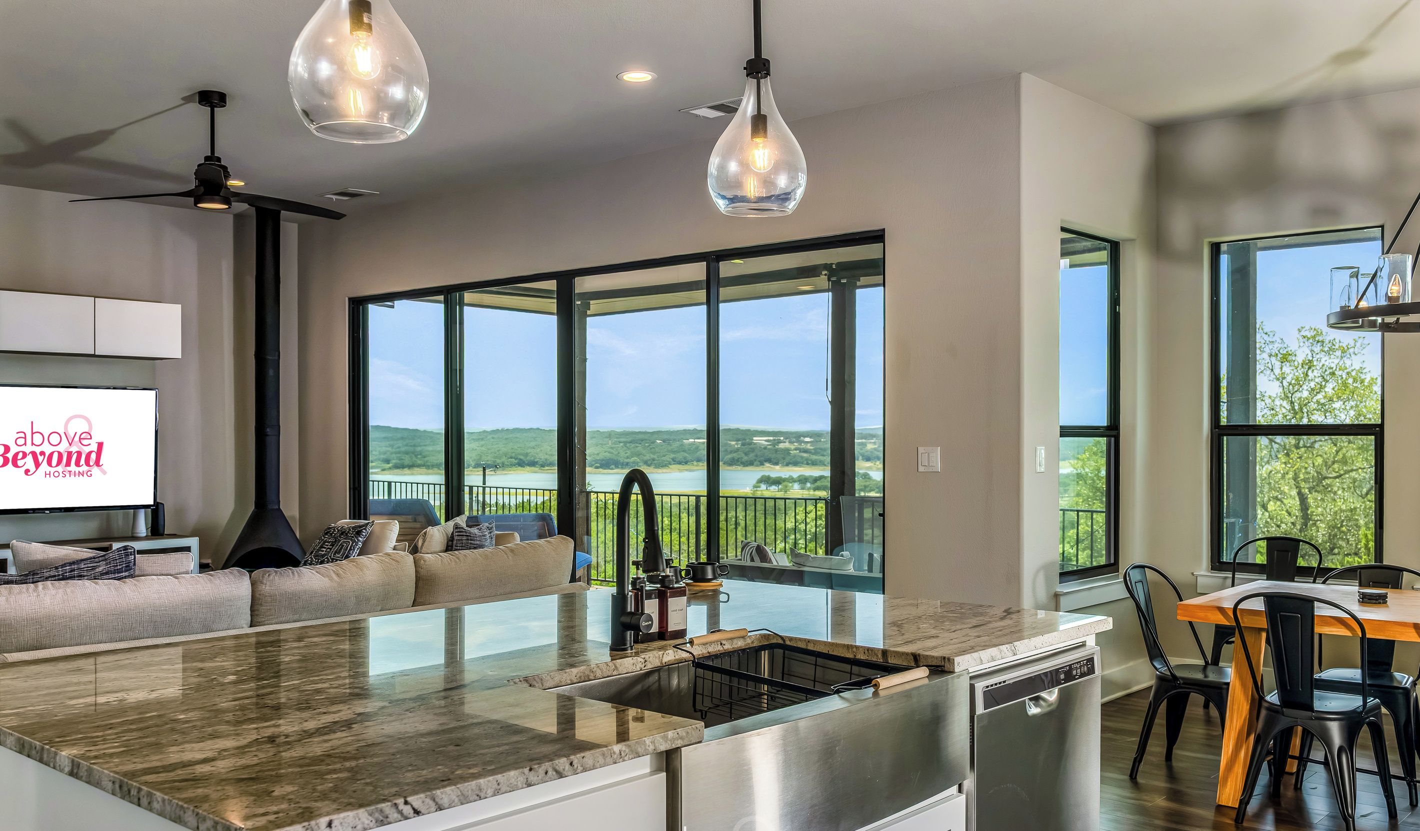 A modern kitchen with a large island, a dining area with a wooden table, and a seating area with a sofa.