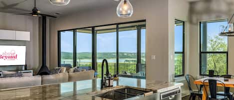 A modern kitchen with a large island, a dining area with a wooden table, and a seating area with a sofa.
