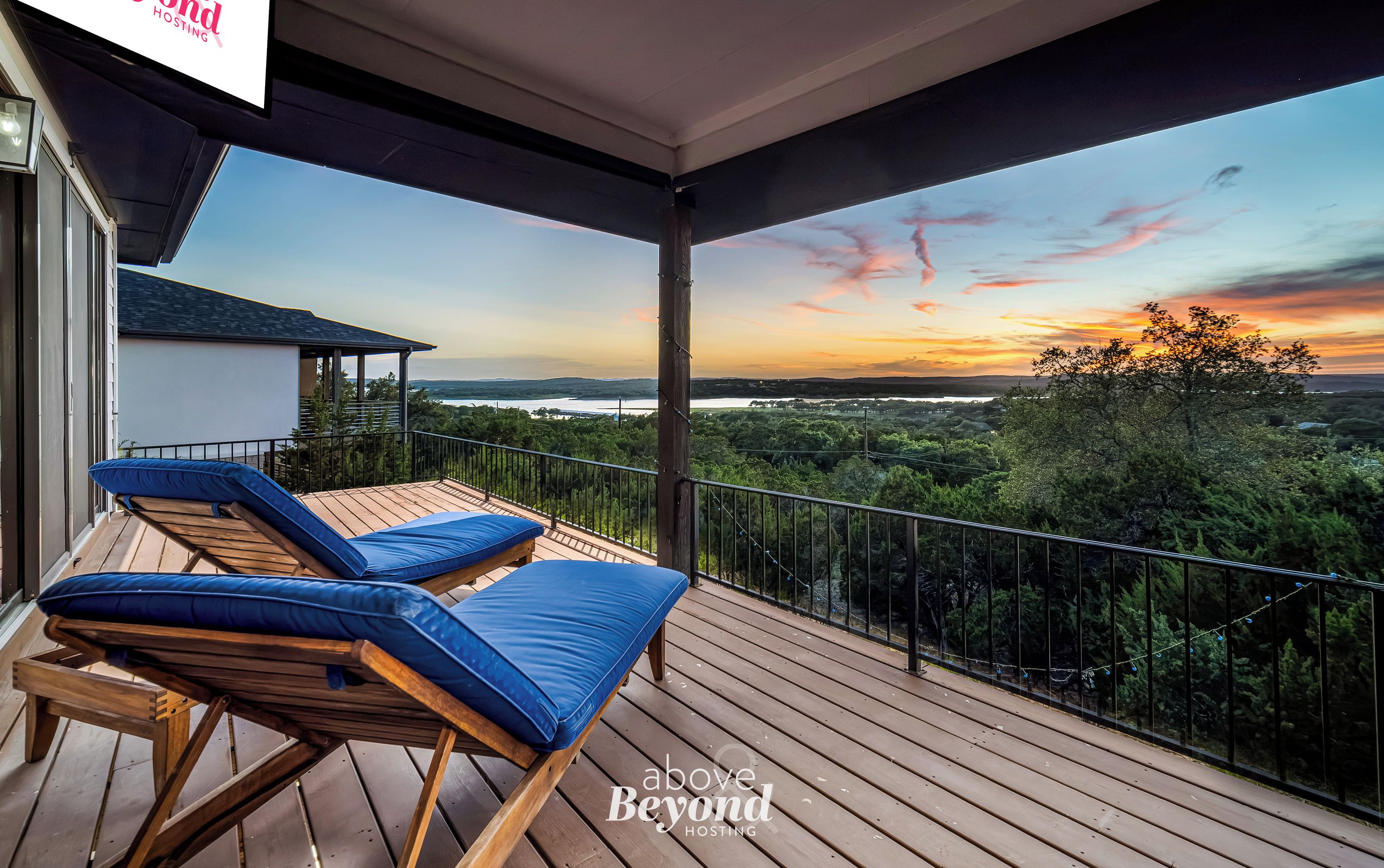 Un balcon avec deux fauteuils et une vue sur un coucher de soleil se déclinant sur un paysage.