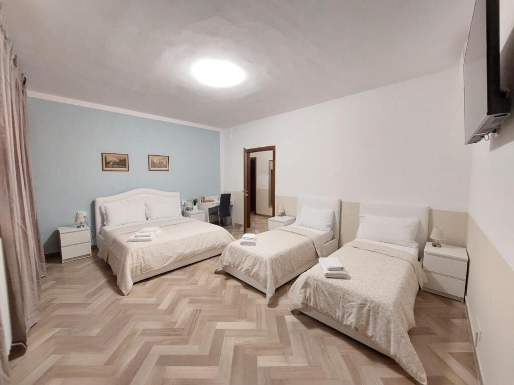 A hotel room with three beds, a desk, a chair, and a mirror.