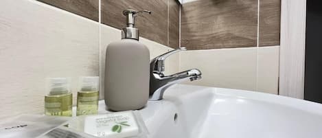 A bathroom with a white sink, a soap dispenser, and a bottle of olive oil.