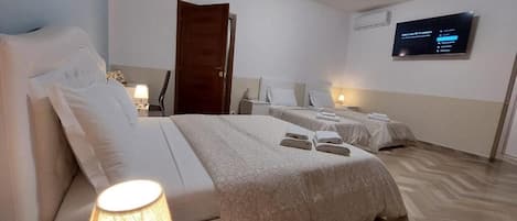 A hotel room with a bed, bedside tables, a TV, and a lamp.