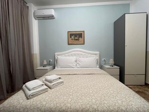 A hotel room with a bed, a wardrobe, a nightstand, and a wall-mounted air conditioner.