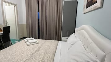 Una habitación de hotel con cama, cortinas, armario, escritorio y silla.