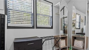 Ein Zimmer mit dunklem Holzkommode, einem Wäscheständer aus Metall, einem grünen Mopp und einer Holzhilfe mit Aufbewahrungsboxen.