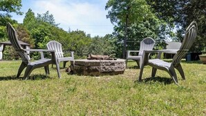 Eine grüne Rasenfläche mit Adirondack-Stühlen und einem Steinkamin.