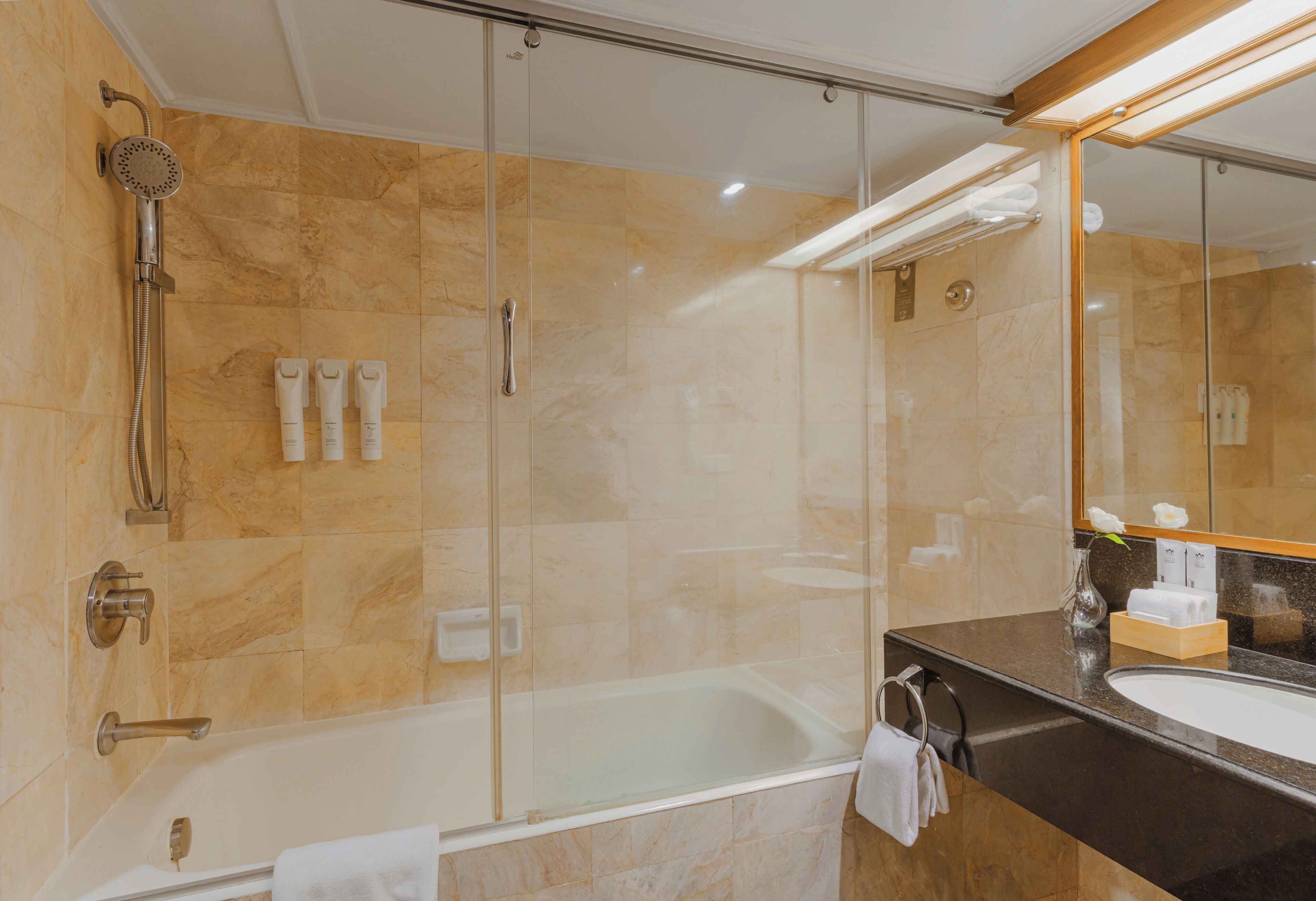 A modern bathroom with a glass-enclosed shower, a bathtub, and a vanity with a mirror.