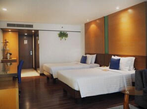 A hotel room with two beds, a glass table, a chair, a desk with a computer, and a plant. - Awtan Sukhumvit (Bangkok)