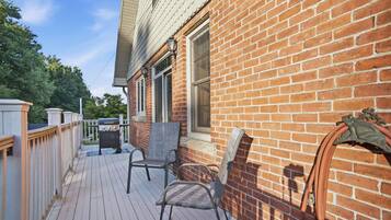 A wooden deck with outdoor seating, a brick wall, and a window.