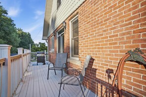 A wooden deck with outdoor seating, a brick wall, and a window.